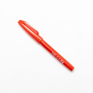 red pen with text "This is a pen", designed by Noritake